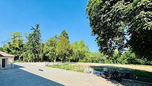 Un espacio pavimentado con un edificio pequeño, cercas y árboles.