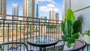 A balcony with a glass table and chairs, overlooking a cityscape with tall buildings and palm trees. - Luxury Studio Retreat with Balcony (Dubai)