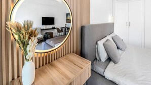 A modern bedroom with a large bed, a bedside table, a mirror, and a TV. - Luxury Studio Retreat with Balcony (Dubai)