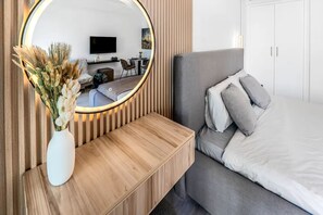 A modern bedroom with a large bed, a bedside table, a mirror, and a TV. - Luxury Studio Retreat with Balcony (Dubai)
