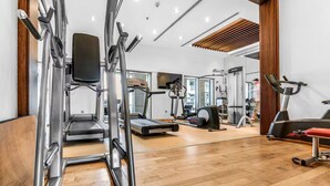A modern gym with various exercise equipment, including treadmills, a weight machine, and a stationary bike. - Luxury Studio Retreat with Balcony (Dubai)