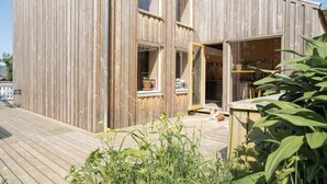 Ein Holzhaus mit großen Fenstern und einer Holzterrasse.