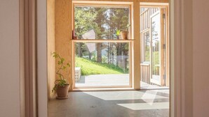 Eine Holztür mit Blick auf eine grüne Landschaft und eine Holzterrasse.
