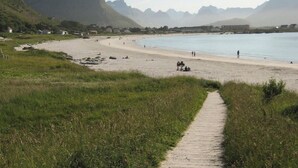 Ein Strand mit einem Pfad zum Ufer, umgeben von Bergen.