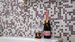 Een fles Moët & Chandon champagne op een badkamermeubel met een betegelde mozaïekachtergrond.