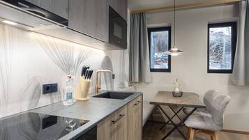 Una cocina moderna con microondas integrado, un lavamanos y una zona de comedor con mesa y silla.