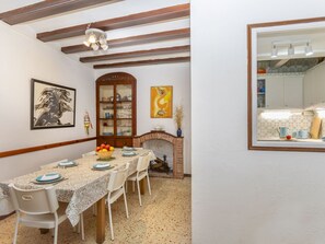 A dining room with a long table, chairs, a cabinet, and a fireplace. - Town Plaza Palafrugell by Interhome (Palafrugell)