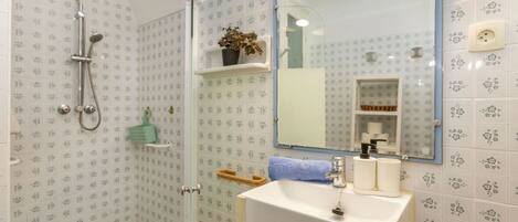 A bathroom with a shower, sink, and mirror.