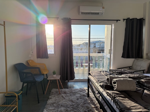 Une chambre moderne avec un lit, une petite table, une chaise et une vue sur la ville grâce à de grandes fenêtres.
