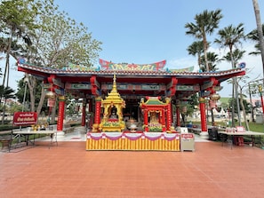 Un templo tradicional con techo rojo y dorado, un santuario central y suelo de baldosas.