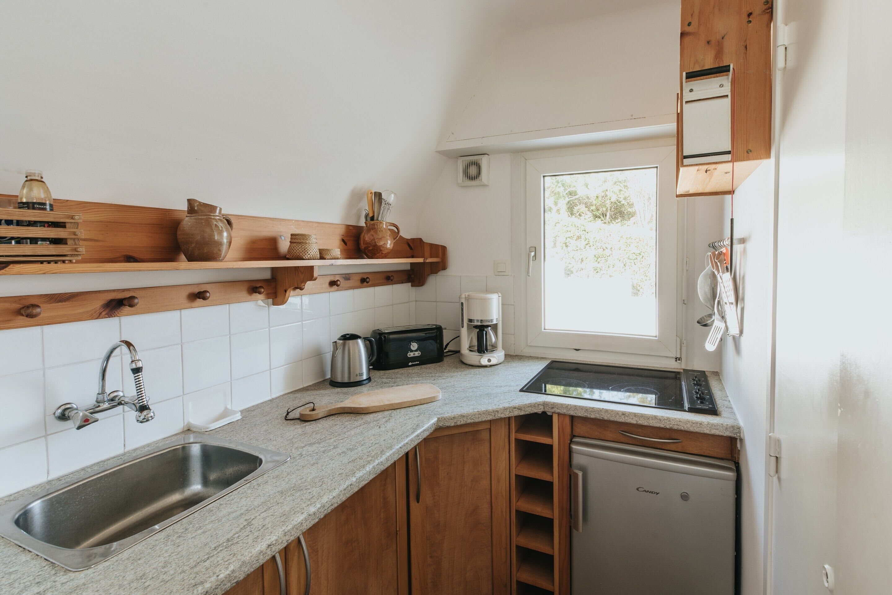 A compact kitchen with a sink, toaster, coffee maker, and a small refrigerator.