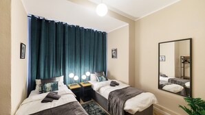 Quarto com duas camas, um espelho grande e uma luminária no teto.