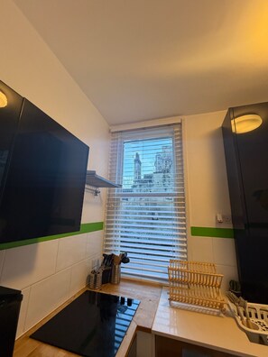 A compact kitchen with a window, a black countertop, and a wooden utensil holder. - Apartment in Bath, Parking Available, Garden Views and Short Walk to Centre (Bath)