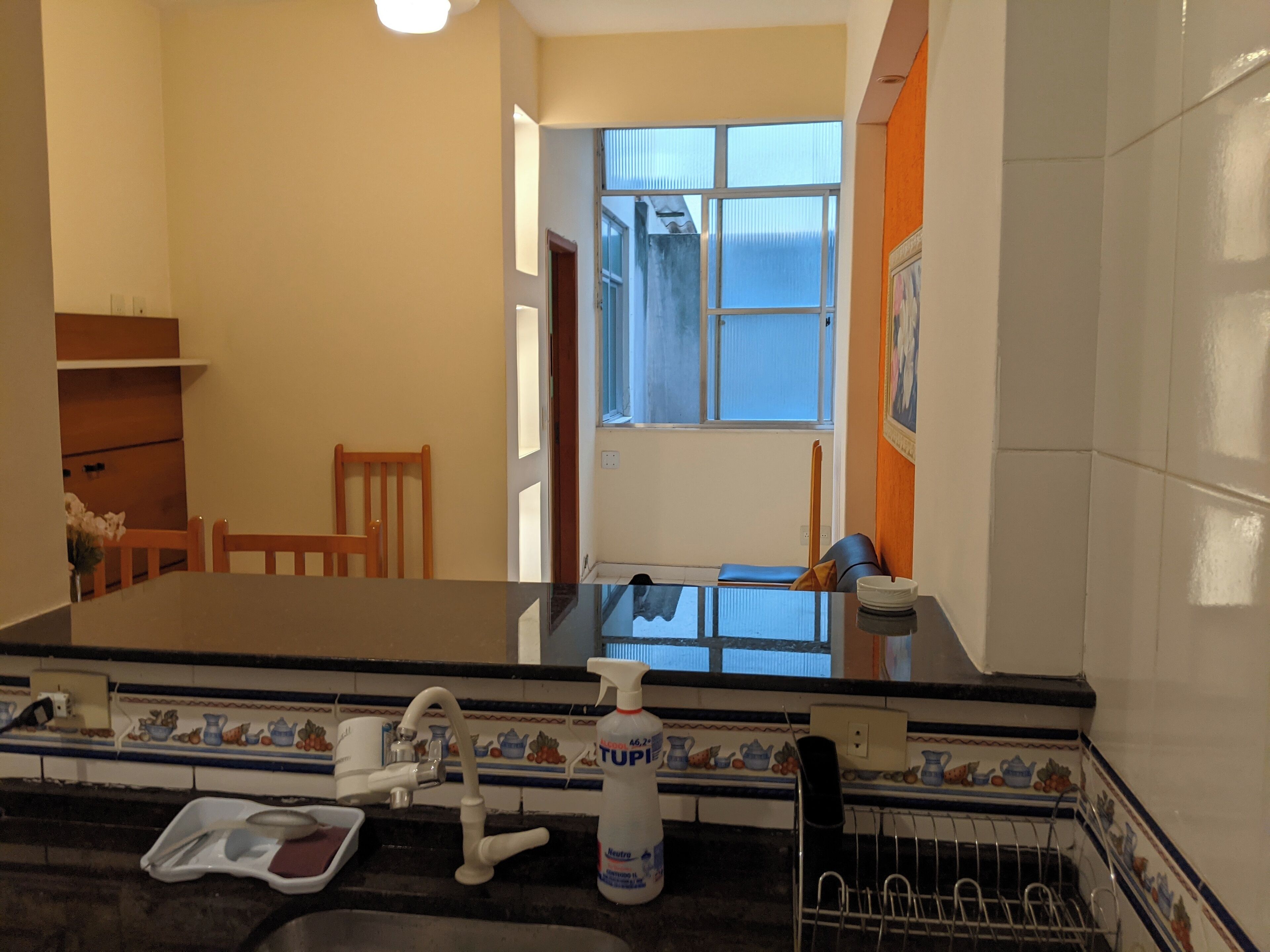 A kitchen with a black countertop, a sink, and a window with blue curtains.