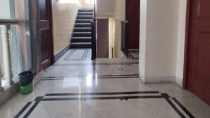 Un pasillo con suelo de mármol, una escalera y una puerta al final.