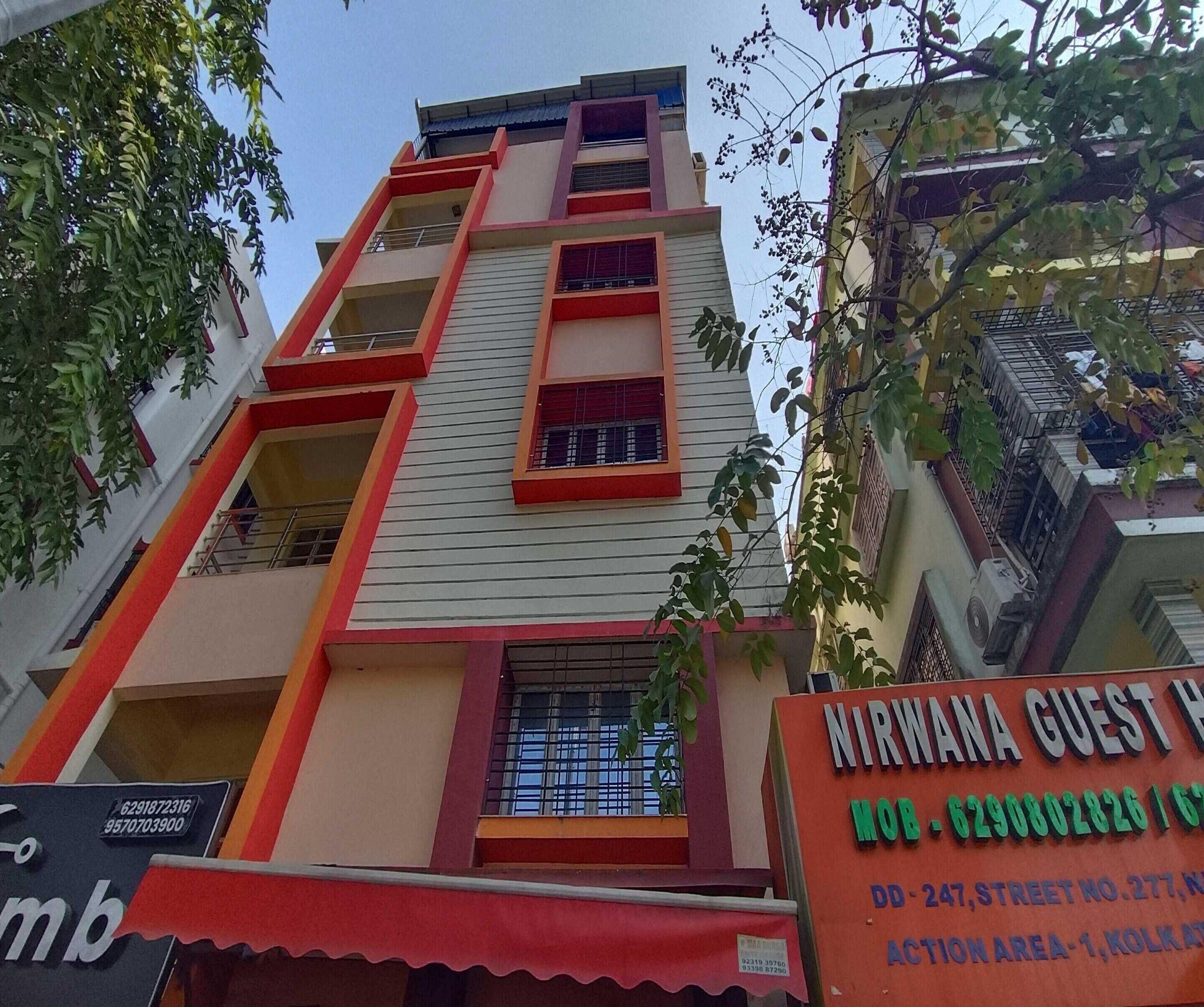 A multi-story building with balconies and a signboard for Nirwana Guest House.