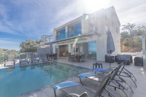 A modern building with a pool area, outdoor seating, and a view of the surrounding landscape. - Protaras Holiday Villa Ds112 (Paralimni)