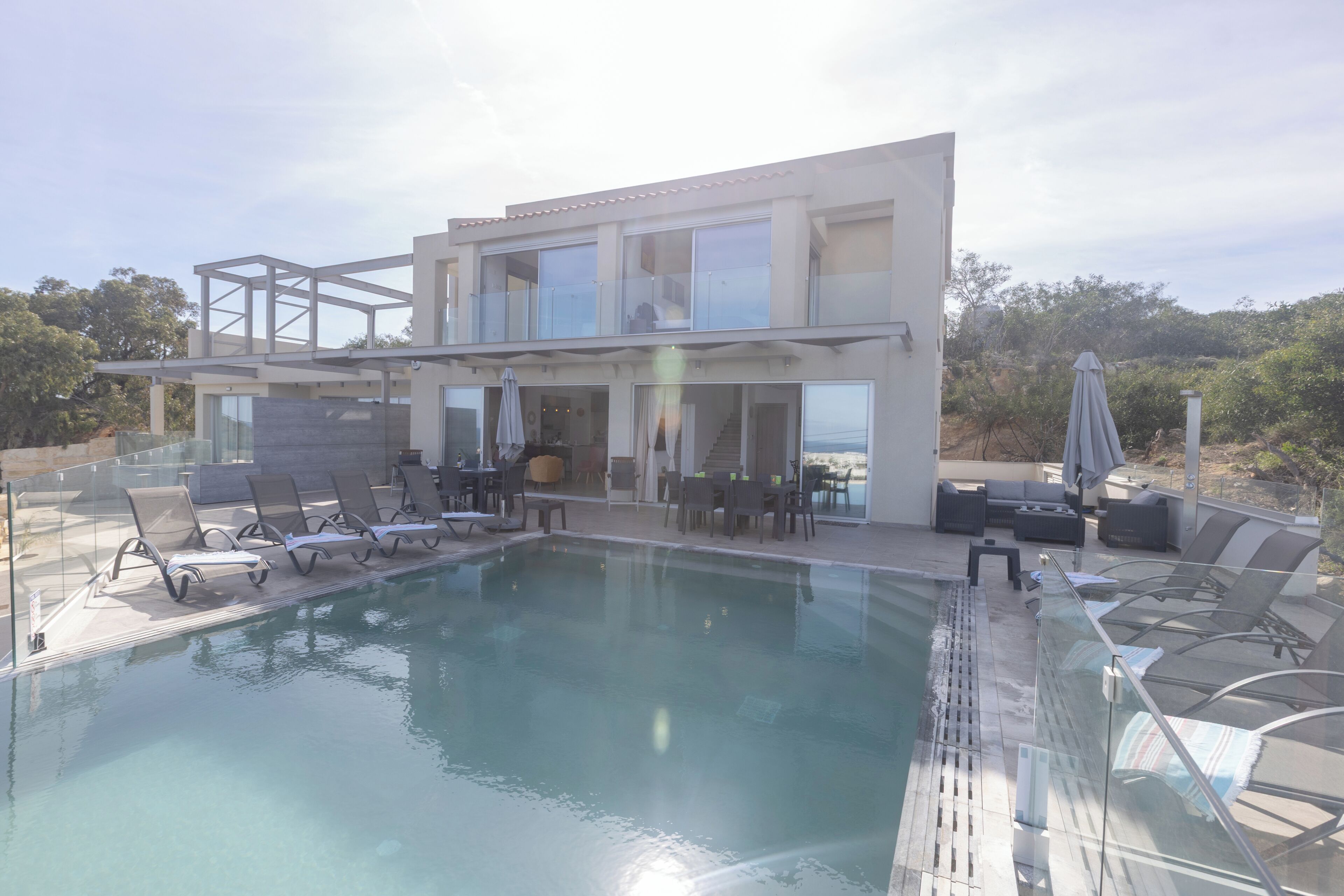 Ein moderner Poolbereich mit Liegestühlen und einem gläsernen Gebäude.