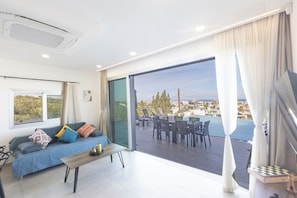 A modern living room with a sofa, coffee table, and a view of an outdoor pool area. - Protaras Holiday Villa Ds112 (Paralimni)