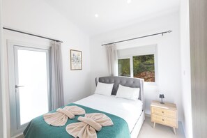 A bedroom with a bed, a nightstand, a window, and a door. - Protaras Holiday Villa Ds112 (Paralimni)