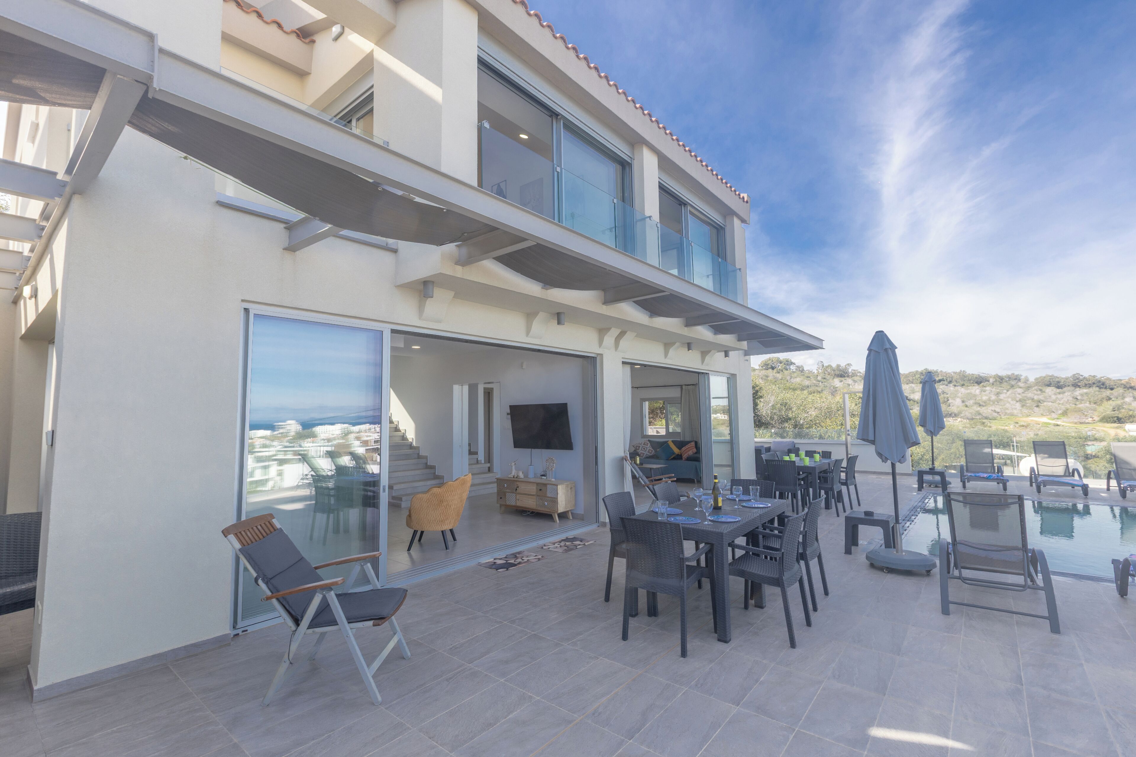 A modern outdoor patio with a dining area, lounge chairs, and a pool.
