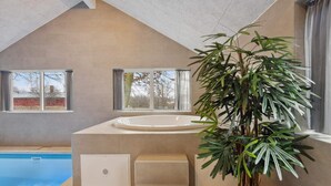 A modern bathroom with a bathtub, a window, and a potted plant. - 5 Star Holiday Home in Glesborg (Glesborg)