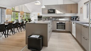 A modern kitchen with a central island, built-in appliances, and a dining area with natural light. - 5 Star Holiday Home in Glesborg (Glesborg)