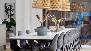 A modern dining area with a long table, black chairs, and three hanging rattan lamps. - 5 Star Holiday Home in Glesborg (Glesborg)