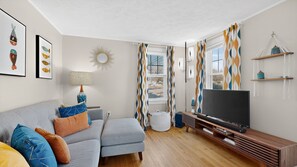 Ein modernes Wohnzimmer mit einem grauen Sofa, einem Fernseher und einer Holz-Unterhaltungsecke.