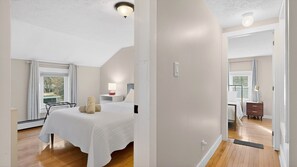 Une chambre d’hôtel avec un lit, un bureau, une chaise, une lampe et une fenêtre avec des rideaux.