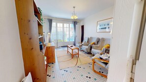 A living room with a sofa, a coffee table, and a wooden cabinet. - Le Porte Bonheur (Saint-Hilaire-de-Riez)