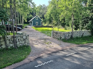 A gravel driveway leading to a house with a stone wall on one side and a white fence on the other. - Private Sauna & Hot Tub Retreat near Omberg (Ödeshog)
