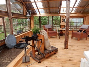 Ein rustikaler Holzraum mit Wintergarten, einem Tisch, Stühlen und einer Katze.