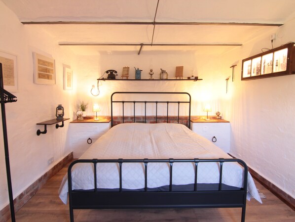 A bedroom with a metal bed frame, wooden flooring, and bedside tables with lamps.