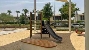 A playground with a slide, climbing structure, and a bench. - Refined Studio w/ Top Facilities in Damac Hills (Dubai)
