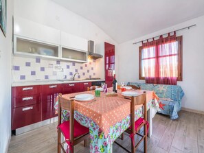 Een koelkast, een oven, een kookplaat, kookgerei, borden en bestek