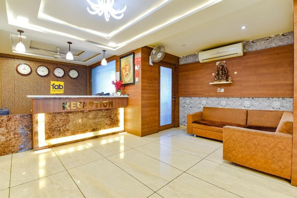 Zona de recepción de un hotel con mostrador, relojes, un sofá y una estatua en la pared.