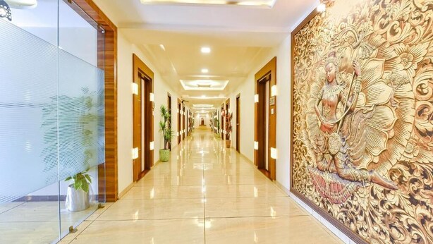 A hotel corridor with a long, polished floor, wooden doors, and a decorative wall mural. - Hotel PVR (Ahmedabad)