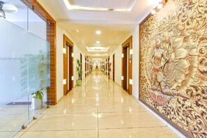 Un pasillo de hotel con un suelo largo y pulido, puertas de madera y un mural decorativo en la pared.