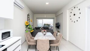 Ein modernes Wohnzimmer mit Esstisch, Sofa und großem Fenster.