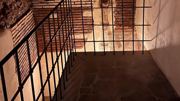 Una scala in pietra con ringhiera metallica che conduce a un arco in mattoni.