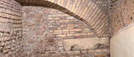 An arched brick ceiling with exposed beams and a metal railing in a rustic interior.