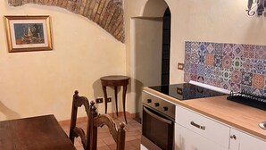 Una cucina compatta con un tavolo in legno, sedie, un fornello e uno schienale piastrellato.