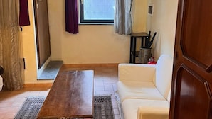 Un soggiorno con un tavolo di legno, un divano bianco, un tappeto decorato e una finestra con tende.