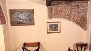 Un'area pranzo rustica con un tavolo e sedie in legno, due quadri appesi al muro e mattoni a vista.