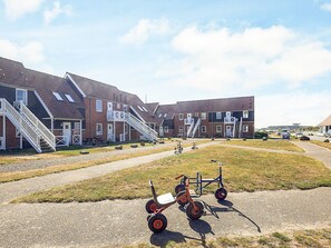 A row of brick buildings with external staircases, a gravel path, and a small wheeled cart in the foreground. - 4 Person Holiday Park Home in Borre (Borre)