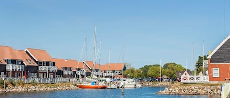 Un puerto deportivo con barcos amarrados, una pequeña isla con un pabellón y edificios con tejados rojos.