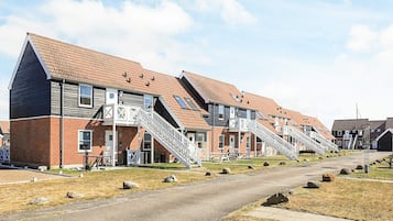 A row of modern apartment buildings with external staircases leading to the entrance.