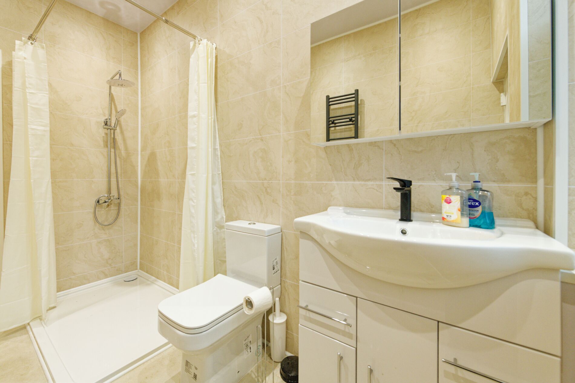 Ein Badezimmer mit Dusche, Toilette, Waschbecken und Ablagekörben.