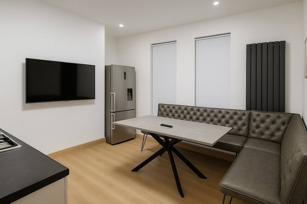 A compact kitchen with a built-in TV, a refrigerator, a dining table, and a sofa.